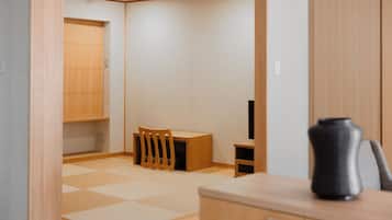 Une pièce au décor minimaliste, avec un plancher en bois, une petite table, une chaise et un meuble.