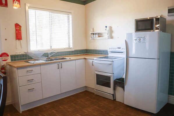 A kitchen with white cabinets, a microwave, a stove, and a refrigerator.