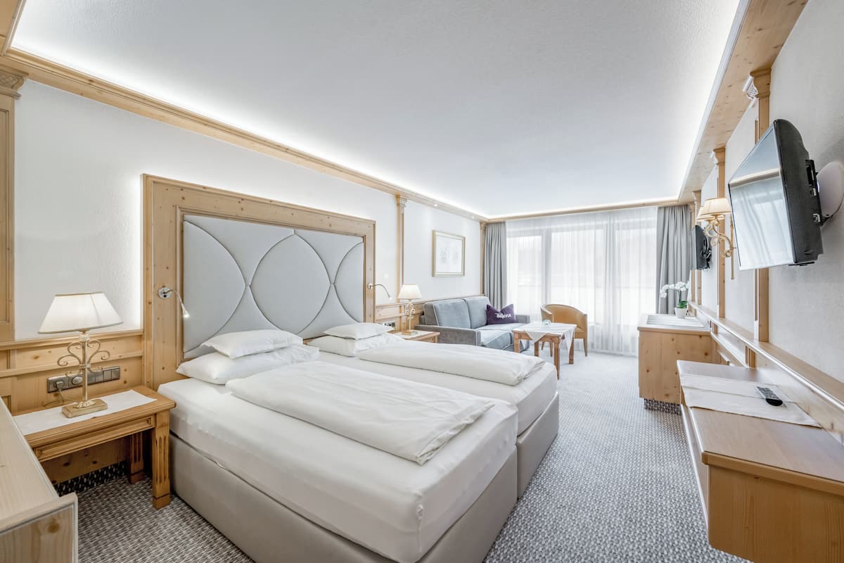 A hotel room with two beds, a desk, a chair, a TV, and a window with curtains.
