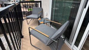 A balcony with two chairs and a table, a glass door, and a view of a residential area. - Enjoyable 1-bedroom condo in Downtown Phoenix with Private garage (Phoenix)