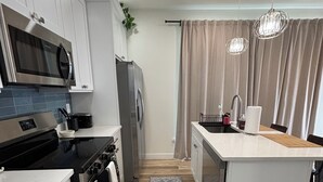 A modern kitchen with white cabinetry, a central island, stainless steel appliances, and a patterned rug. - Enjoyable 1-bedroom condo in Downtown Phoenix with Private garage (Phoenix)