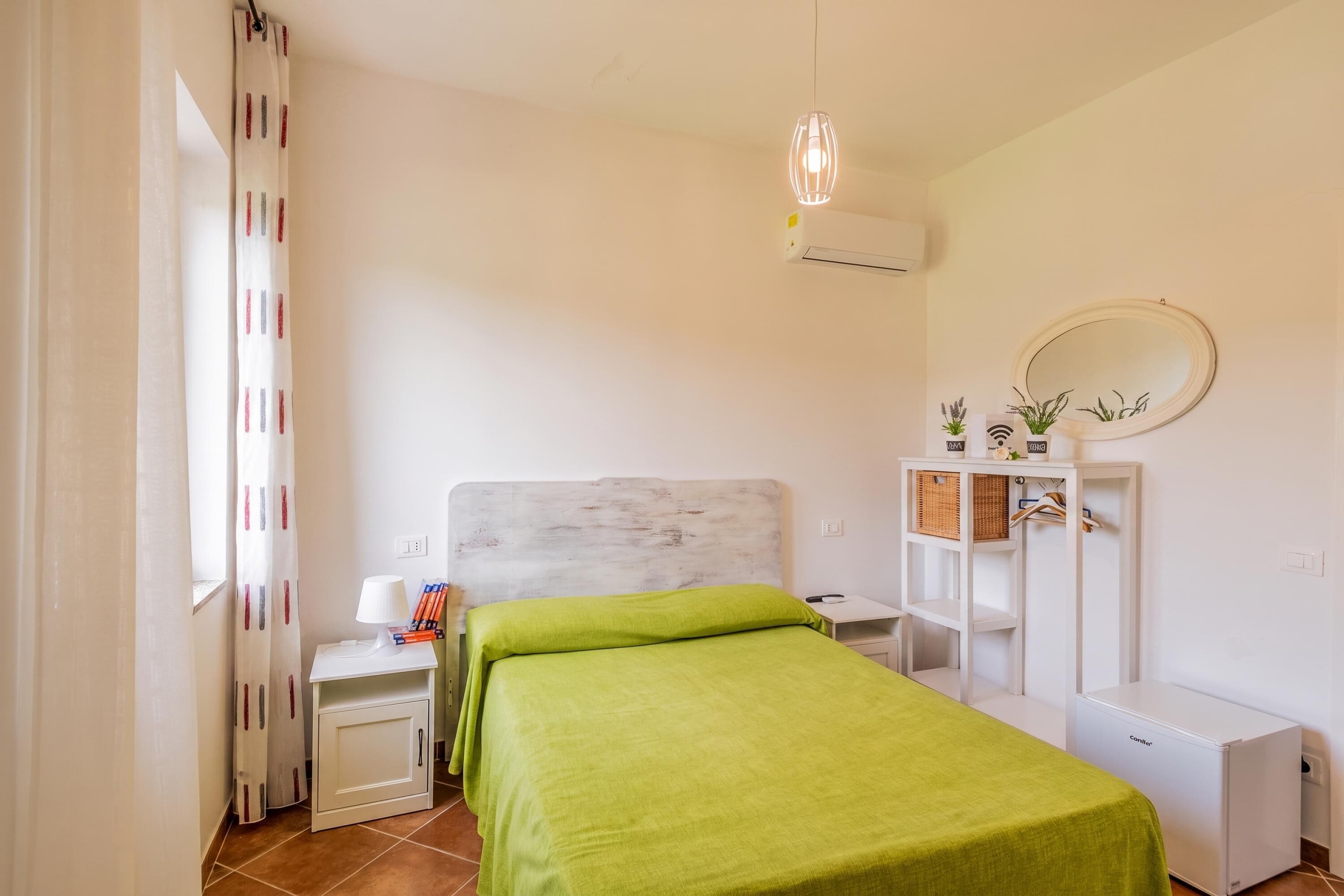 Un dormitorio con cama, mesitas de noche, armario, espejo y lámpara colgante.