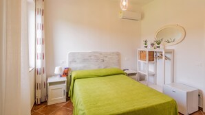 Un dormitorio con cama, mesitas de noche, armario, espejo y lámpara colgante.
