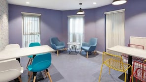 A room with a white table, blue chairs, a small round table, and a yellow chair. - Student Only Frobisher House (Plymouth)