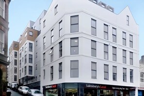 A multi-story building with a corner entrance, featuring a store named 'Sainsbury's Local' on the ground floor. - Student Only Frobisher House (Plymouth)