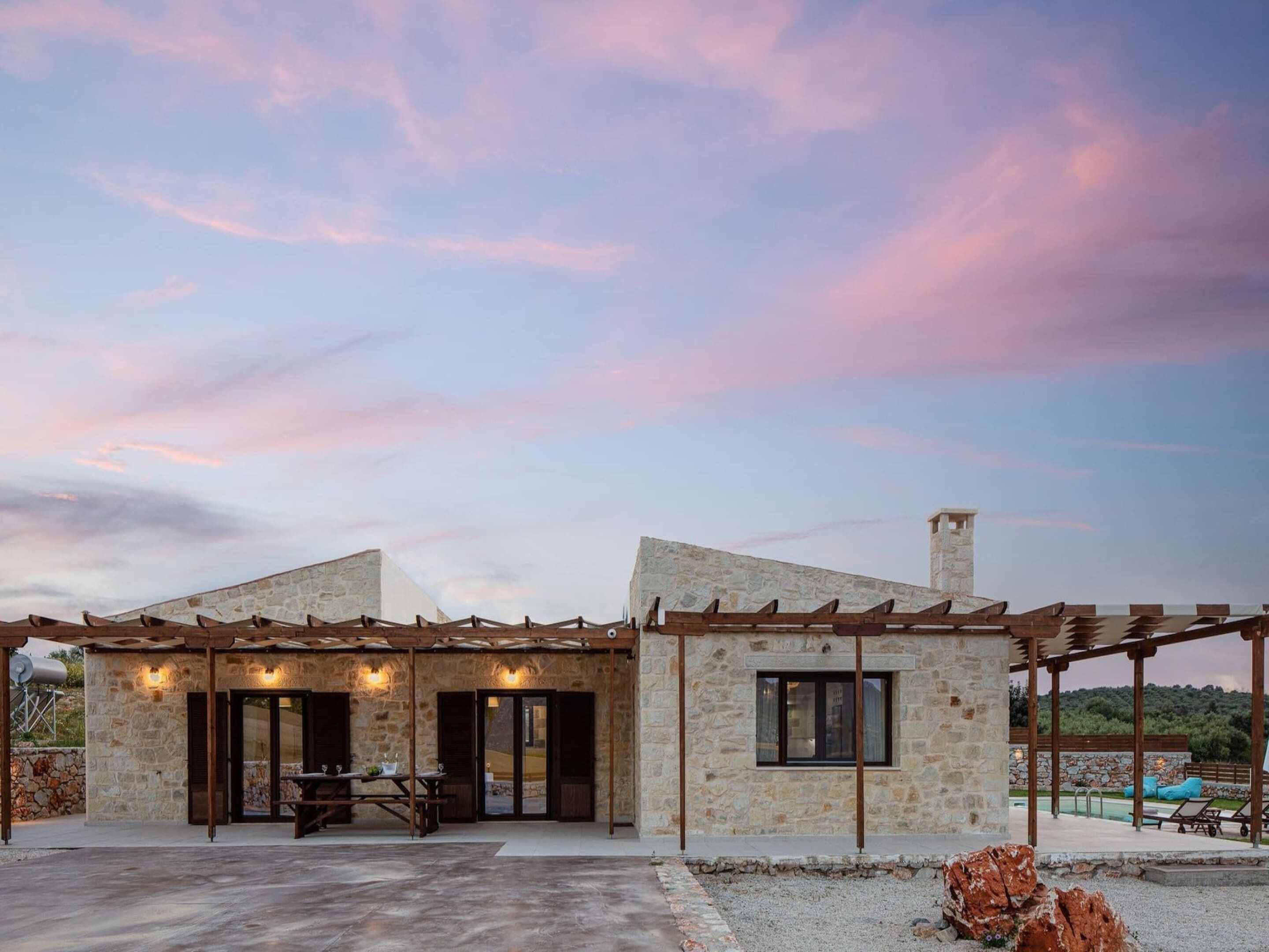 Un edificio de piedra con patio cubierto, mobiliario exterior y zona de piscina.