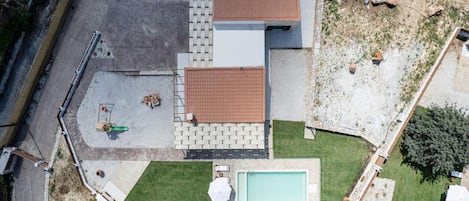 Vista aérea de una propiedad residencial con piscina, patio y jardín pequeño.