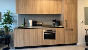 Eine moderne Küche mit Holzschränken, einem Bosch-Ofen, einer Kaffeemaschine und einer Pflanze.