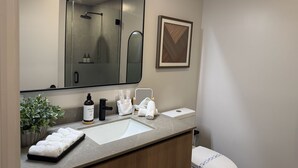 Ein Badezimmer mit großem Spiegel, Waschbecken, Toilette und einem gerahmten Bild an der Wand.
