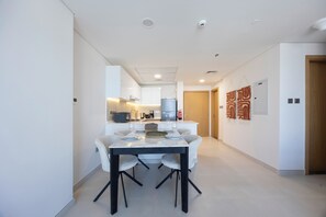 Eine moderne Küche mit Essbereich, weißen Wänden und einer Holztür.
