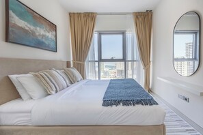 Ein Hotelzimmer mit einem großen Bett, Blick auf die Stadt und einem Bild an der Wand.