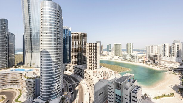 Een hoog gebouw met een golvend ontwerp, een strand en een heldere lucht.