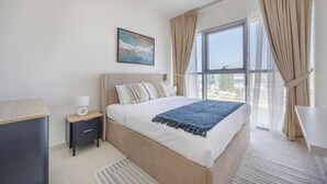 Een moderne slaapkamer met een groot bed, nachtkastje, een raam met gordijnen en uitzicht over de stad.