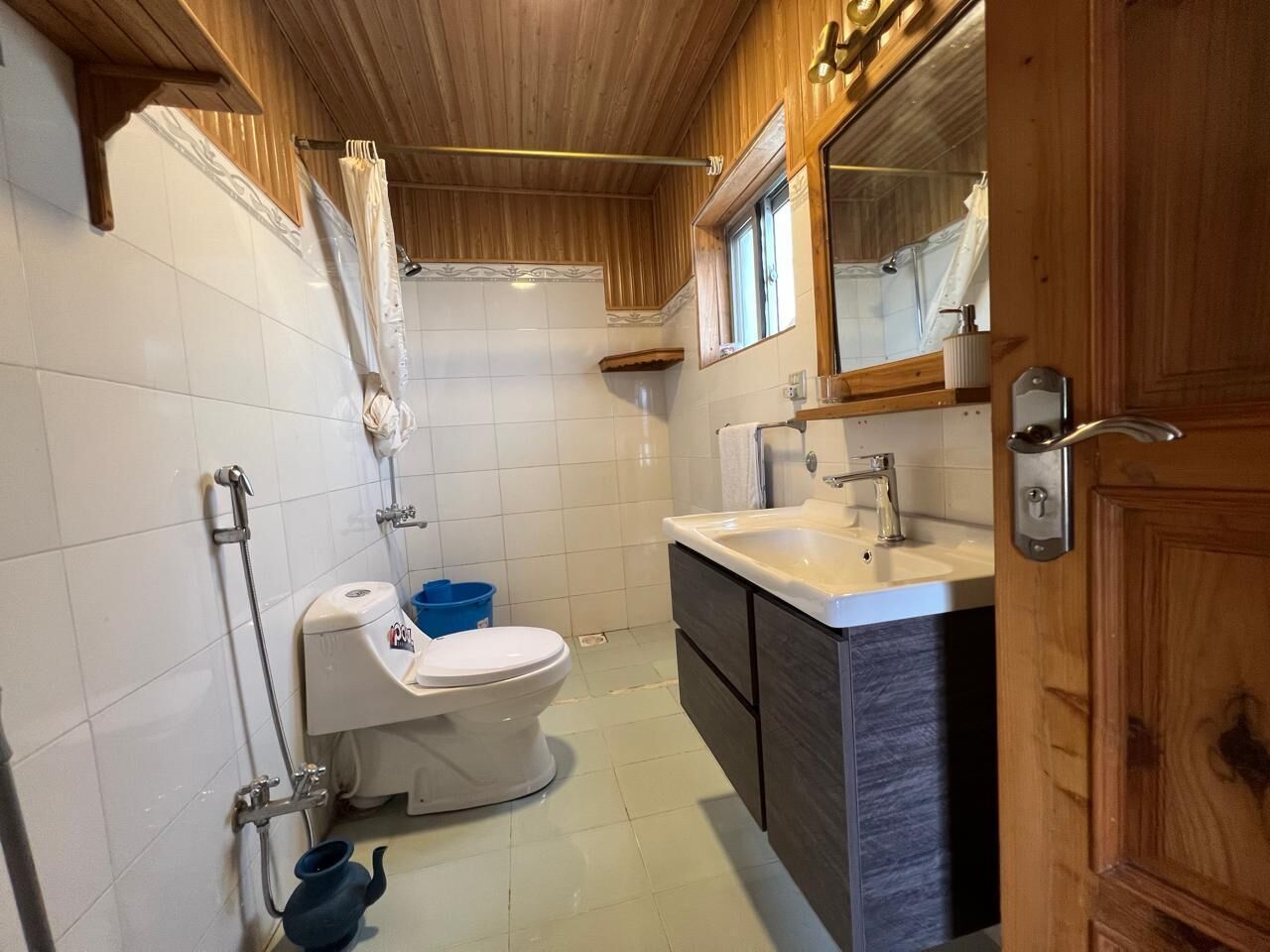 Une salle de bain équipée de toilettes, d’un lavabo, d’une douche et de meubles en bois.