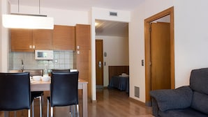 A modern kitchen with wooden cabinets, a dining table with chairs, a sofa, and a door leading to another room. - Terrace Apartment for 4 in Pals (Pals)