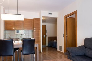 Eine moderne Küche mit Holzschränken, einem Esstisch mit Stühlen, einem Sofa und einer Tür zu einem anderen Raum.