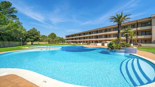 A hotel with a swimming pool, a multi-story building, and a landscaped area with trees. - Terrace Apartment for 4 in Pals (Pals)
