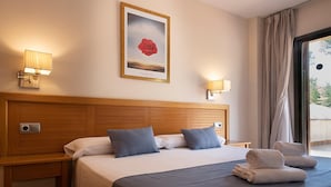 A hotel room with a large bed, two bedside lamps, a framed picture on the wall, and a view through the window. - Terrace Apartment for 4 in Pals (Pals)