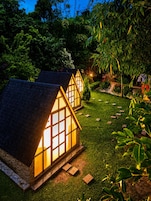 Una hilera de pequeñas y acogedoras casitas con techos de paja y ventanas grandes, rodeadas de exuberante vegetación.