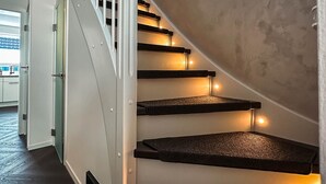 Eine Treppe mit weißen Geländern und schwarzen Stufen, die zu einem Zimmer mit Aussicht führt.