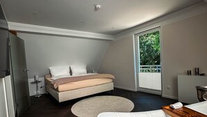 Ein modernes Schlafzimmer mit einem großen Bett, einer Badewanne und Blick auf Grünfläche.