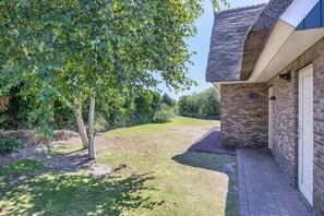 A brick building with a number 8 sign, a paved driveway, and a grassy area with trees. - Luxury Beach Villa in Makkum With Sauna (Makkum)