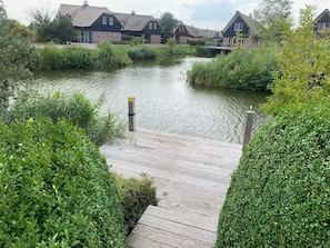 Une jetée en bois qui mène à un canal, avec des maisons en arrière-plan.