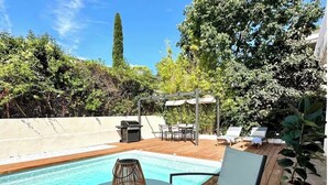 A wooden deck with a pool, outdoor furniture, and a pergola with umbrellas. - La Villa du Sud - Standing & Calme, 20mn Plages (100% climatisée) (Montpellier)