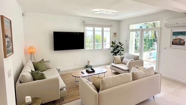A modern living room with a sofa, coffee table, and a TV mounted on the wall. - La Villa du Sud - Standing & Calme, 20mn Plages (100% climatisée) (Montpellier)