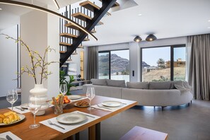 A modern dining area with a wooden table set for a meal, a staircase, and a view of a mountainous landscape. - Maple Villa 1 Deluxe Sea View Villa in Walking Distance From Beach (Agios Vasileios)