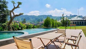 Uma área à beira da piscina com espreguiçadeiras e vista para uma paisagem montanhosa.