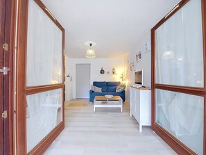 Ein Flur mit einem blauen Sofa, einem weißen Schrank und einer Glastür mit Holzrahmen.