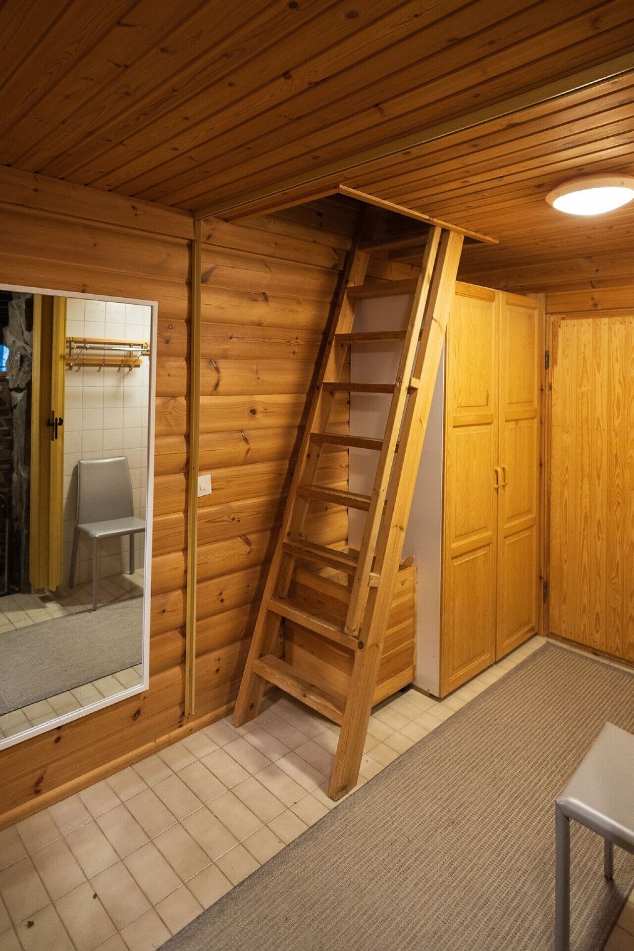 Un intérieur en bois avec une échelle en bois, une porte et une chaise.