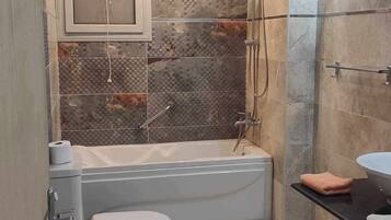 Un baño con bañera, inodoro y zona de ducha.