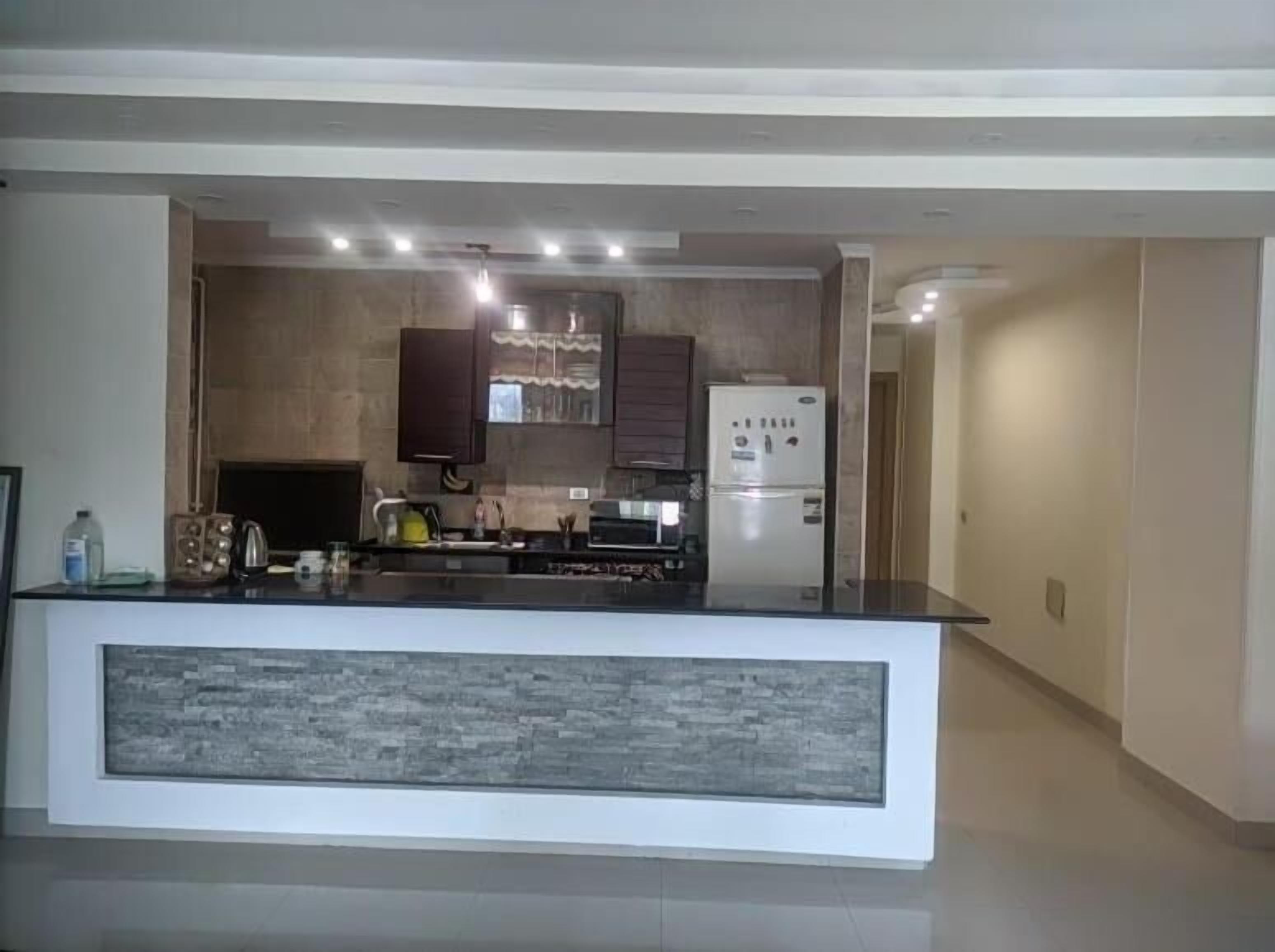 Una cocina moderna con una isla central, electrodomésticos integrados y una luz empotrada en el techo.