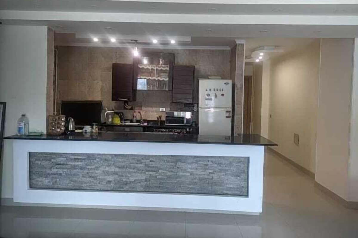 A modern kitchen with a central island, built-in appliances, and a recessed ceiling light.