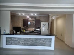Cocina moderna con isla central, electrodomésticos integrados y foco empotrado en el techo.