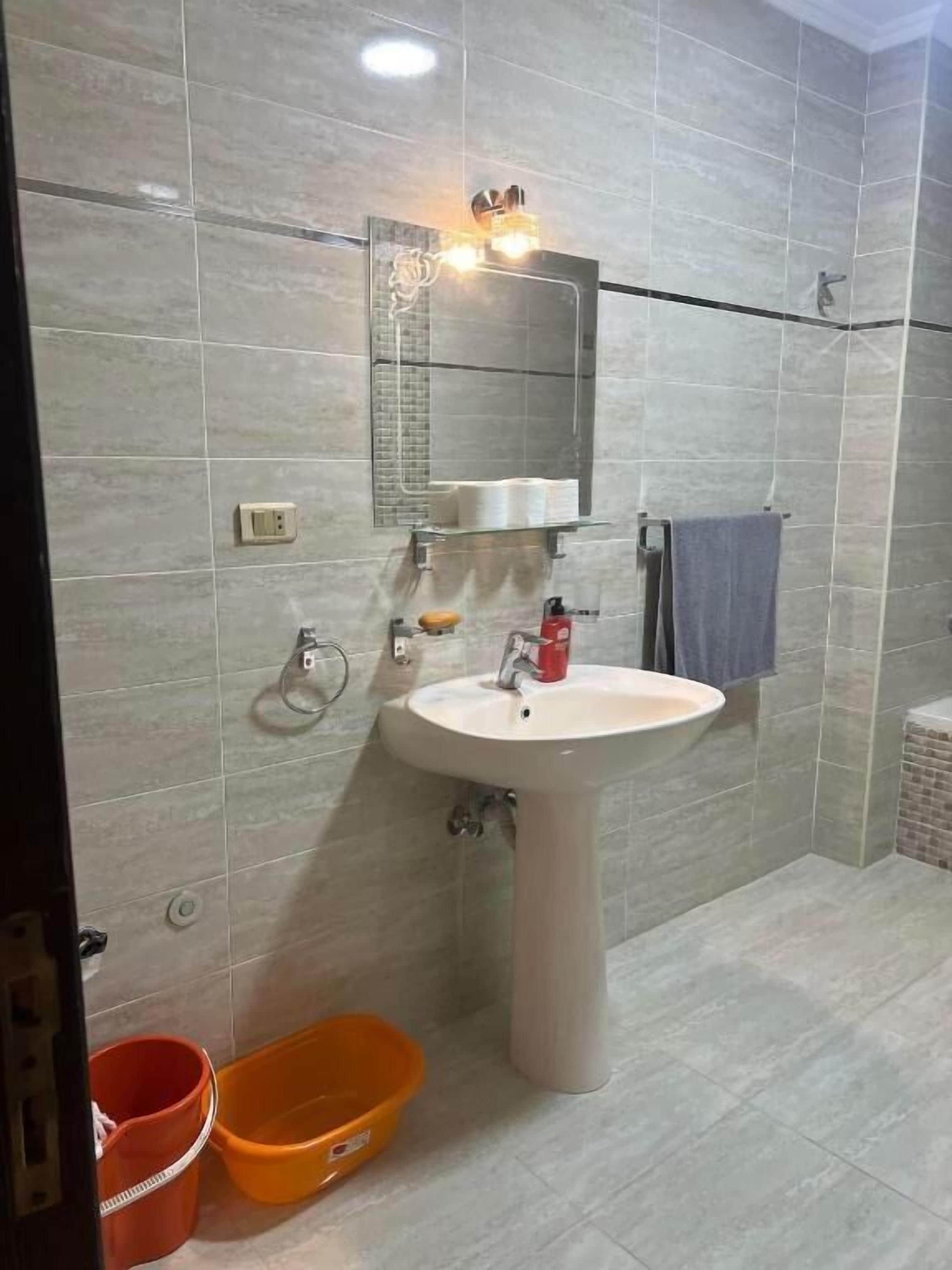 A bathroom with a pedestal sink, a mirror, a towel rack, and a shower area.