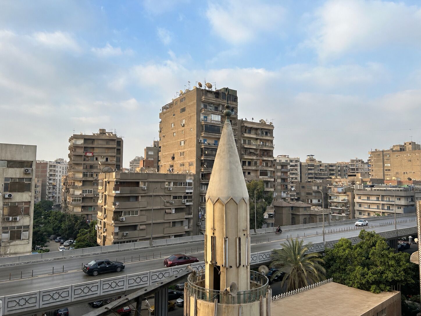 A cityscape with a prominent tower and a busy road with vehicles.