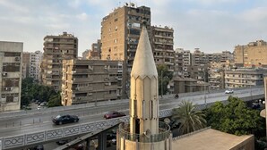 A cityscape with a prominent tower and a busy road with vehicles.