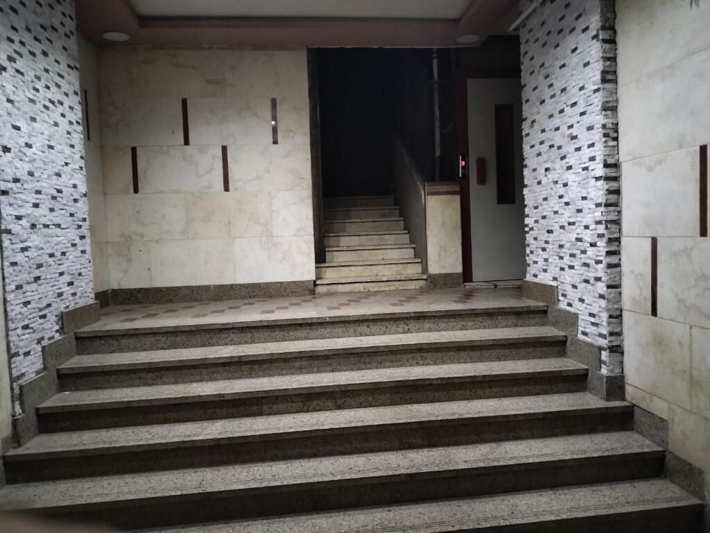 Una escalera conduce a un interior oscuro, flanqueada por paredes con un diseño de baldosas estampadas.