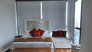 Ein Hotelzimmer mit einem großen Bett, einem Schlafsofa, einem Nachttisch und Blick auf die Stadt durch das Fenster.