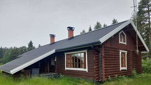 A log cabin with a sloped roof, two chimneys, and a front porch. - Varpunen - Peaceful 2BR Cabin in Ruka (Kuusamo)