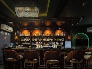 Una zona de bar con candelabro, estanterías en arco y taburetes.