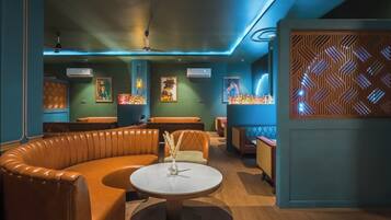 Un espace de détente moderne avec des sièges en cuir, une table ronde centrale et des œuvres d’art décoratives murales.