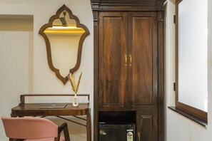 Une pièce comprenant un meuble en bois, un bureau avec un ordinateur portable, une chaise et un réfrigérateur.