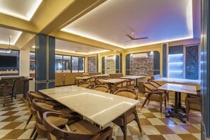 Ein Restaurant mit Schachbrettboden, Holztischen und -stühlen sowie einem Deckenventilator.