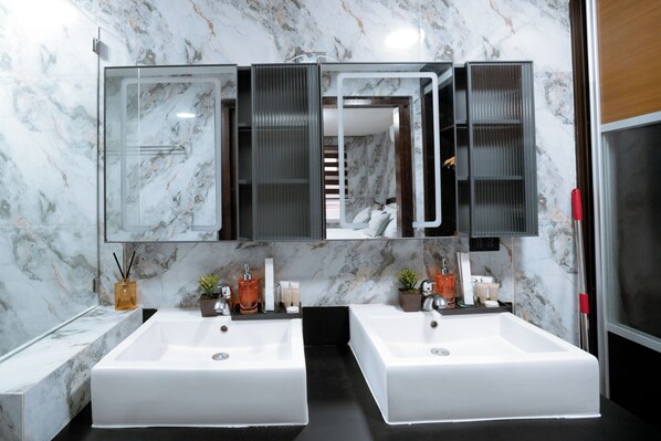 A bathroom with two white sinks, a large mirror, and a marble backsplash.