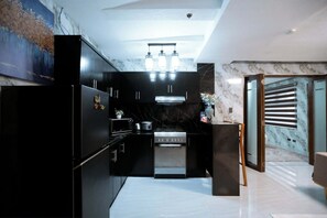 A modern kitchen with black cabinetry, a stainless steel oven, and a marble backsplash. - Spacious fully self-contained 1-bedroom condo in Angeles City near Clark (Angeles)