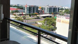 A balcony with a table and chairs, overlooking a cityscape with modern buildings and a McDonald's. - Spacious fully self-contained 1-bedroom condo in Angeles City near Clark (Angeles)